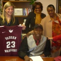 <p>Dashawn Johnson, center, a student at Martin Luther King Jr. High School in Hastings, signs his commitment to attend Vaughn College.</p>