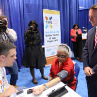 <p>Westchester County Executive Robert P. Astorino watches as volunteer technician João Pinto, a student at Pace University, takes the vital signs of Shirley Hunter, a resident of the Soundview Apartments at United Hebrew in New Rochelle.</p>