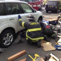 <p>Fairfield and Bridgeport firefighters work together to raise the vehicle to pull an injured woman out from under it. </p>