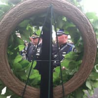 <p>Stamford Police Assistant Chief James Matheny, at left, and Officer Ryan McAllister, at right, scene through a wreath placed in memory of Stamford Police officers who died while on duty. </p>