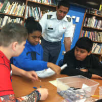 <p>West Point Military Cadet Derrick Hall helps from left Cloonan Middle School students John Liberatore, Daria Domond and Uriel Tofino during a robotics event Tuesday to help spark students interest in science, math and engineering.</p>