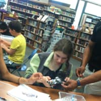 <p>West Point Military Academy assistant math professor Dr. Kendall Williams, helps Shauna Alexander, left, and Leila Manojlovic, center, during robotics event at Cloonan Middle School Tuesday.</p>