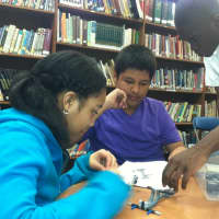 <p>Cadet Lewis Black helps Jayla Scales, left, and Jharif Rochabrun, center, during the robotics event at Cloonan Middle School.</p>