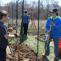 <p>Volunteer Doni Wisdom (right) stops to chat with Boy Scout Christopher Lanni as they work at Graces Hill Farm, a new community garden at Our Saviours Lutheran Church in Fairfield last year.</p>
