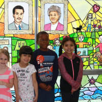 <p>Several of the Lee F. Jackson first-grade artists who created the stained-glass work stand in front of the exhibit.</p>