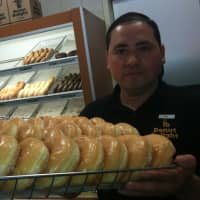 <p>Salvador Carrera, manager of the Donut Delight location at 274 Hope St., holds up a tray of honey dip doughnuts on National Donut Day.</p>