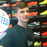 <p>Soccer &amp; Rugby Imports assistant manager Austin Murray holds a small U.S. soccer ball. He said the 42 W. Putnam Ave., store has seen steady business leading up to the World Cup, which begins Thursday in Brazil.</p>