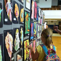 <p>Students visit the all-purpose room and look for their artwork on the wall. </p>