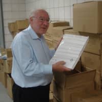 <p>Needs Clearing House Co-President Joe Kaliko holds up one of the 14,000 bed sheet sets donated by Starwood and temporarily housed at Westy Self Storage in Norwalk.</p>