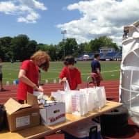 <p>Will Graney-Green (left) and Ryan Chesney fill luminaria bags with canned goods at Fairfield&#x27;s Relay for Life.</p>