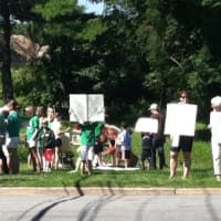 <p>Fairfield residents hold a protest Saturday as they seek to have sound barriers built at the I-95 northbound rest area. Construction materials can be seen behind them at the Exit 22 rest stop.</p>