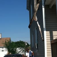 <p>A city official and a resident, in back, clear debris from a fire Tuesday at 46 Leeds St. No one was hurt in the fire. Some of the debris fell on an Audi A4 2.0 Turbo parked in the driveway.</p>