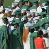 <p>The graduates are dressed in the traditional green and white at Norwalk High School. </p>