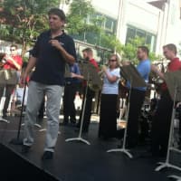 <p>Boston Pops Music Director Keith Lockhart snaps his fingers as a smaller version of his famous orchestra performs on Bedford Street on Monday. The event was held to promote the live web streaming of its popular July 4 concert.</p>