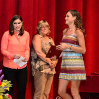 <p>A student walks across the stage to receive her award.</p>