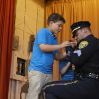 <p>New Fairfield Police Sgt. Edward Nook has his two sons, 5-year-old Zackery and 9-year-old Edward, help him pin his new badge to his uniform. </p>