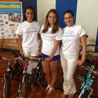 <p>Cristiana (left) and Lucia Villani (center) and their mother Adriane Defeo (right) help give away bikes to kids.</p>