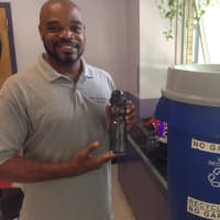 <p>Byron Smalls displays reusable water bottles donated by the state police. </p>