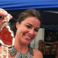 <p>Meredith Bagley of Norwalk holds up one of her creations, a coral with an agate pendant necklace at New Canaan&#x27;s annual Village Fair and Sidewalk Sale on Saturday.</p>