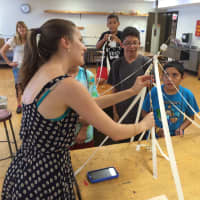 <p>Mimi Zimmer measures the length of a spaghetti structure built to support a marshmallow on top. </p>