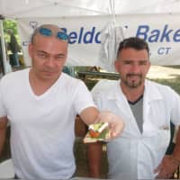 <p>Fernando Castano, left, holds a sample, while Giovanni Castano, owner of Beldotti Bakeries looks on at the Wilton Farmers Market.</p>