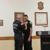 <p>Elmsford Police Commissioner Frank Rescigno pins his own first badge on the newest Elmsford Police Officer, Paul Rescigno, his son.</p>