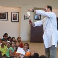 <p>Delighted children look on as Jonah Cohen, the Science Genie from the Children&#x27;s Museum, performs an experiment above their heads at the Ferguson Library on Thursday.</p>