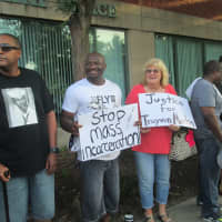 <p>Tyrone Welch and Anne Wagner hold up signs calling for justice at a rally for Michael Brown.</p>
