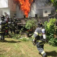 <p>Flames are visible as Norwalk firefighters arrive at the home on Riverside Avenue on Thursday.</p>