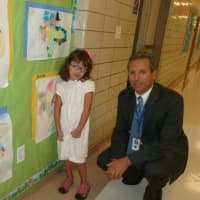 <p>Julia A. Stark School first grade student Zoe Guaman looks at some artwork on the wall along with her principal Mark Bonasera on the first day for Stamford Public Schools on Tuesday.</p>