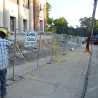 <p>Construction workers fence off the construction site to open the sidewalk to pedestrian access for the start of school.</p>