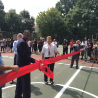 <p>Rochambeau School Director Paul Pratcher cuts the ribbon on a new basketball court Friday. </p>