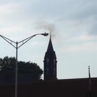 <p>Smoke can be seen coming from the steeple at Little Zion Church of Christ after it was struck by lightning Saturday afternoon.</p>