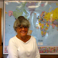 <p>Pat Atkin of Atkin &amp; Co. sits in front of the world map marked with locations that have received wooden boat plans from her 108 -year-old Darien business. </p>
