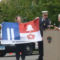 <p>Diane Wells, right, regent of the Hannah Benedict Carter chapter of the Daughters of the American Revolution presents a flag to New Canaan first responders. Each part of the flag represents the three areas involved in the 9/11 attacks.</p>