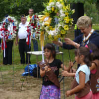 <p>Larchmont-Mamaroneck Girl Scouts place one of three wreaths in front of the Girl Scout Rock Memorial. </p>