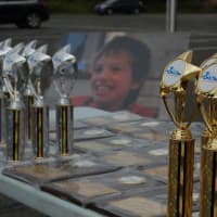 <p>A picture of Mikey Fedak sits behind trophies at the awards table.</p>