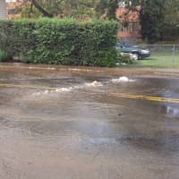 <p>Water spills onto the street following a main break in South Norwalk Wednesday.</p>