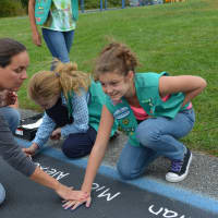 <p>Sixth-grade Girl Scout Mia Castellano places her hand print on the mural at Pequenakonck Elementary School.</p>