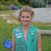<p>Sixth-grade Girl Scout Mia Castellano shows her blue hand after she placed her handprint on the Pequenakonck Elementary School mural.</p>
