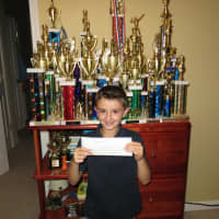 <p>Avery Hood, 7, a Hudson County Montessori student in New Rochelle, with one of his checks and some of his chess trophies.</p>