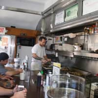 <p>Sprague works behind the counter to cook meals for guests. </p>