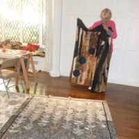 <p>Doris Ieva folds a quilt she created while a second one she made is spread on the floor at the Stamford Museum &amp; Nature Center.</p>