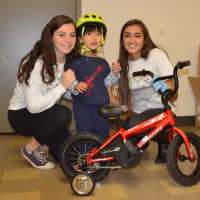 <p>The teens present a bike to a young boy. </p>