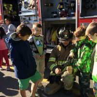 <p>A fireman teaches young boys about the fire hose. </p>