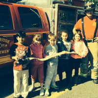 <p>Students and a fireman pose with the fire hose. </p>