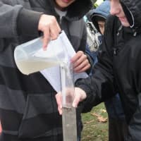 <p>Students and teachers measure water. </p>