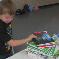 <p>Royle first-grader Max Scaccia organizes notebooks for Bridgeport foster care children.</p>