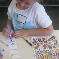 <p>Royle student Ashlyn Fran makes a bookmark for a Bridgeport foster care child.</p>