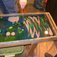 <p>A fairgoer experiments with the ancient water-marbling technique to create a one-of-a-kind scarf by Shibumi Silks.</p>